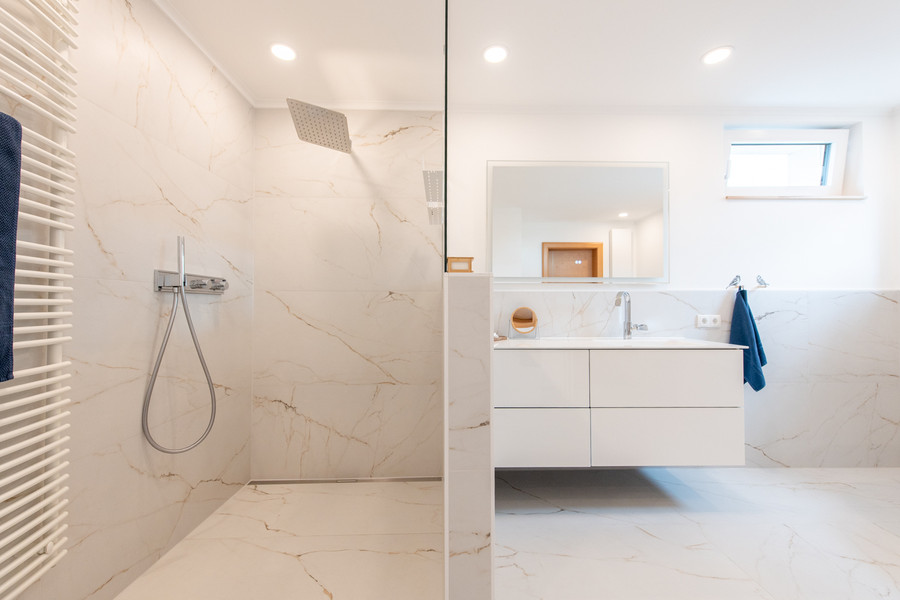 bodenebene Walk-In Dusche mit hellen Fliesen, Thermostatarmatur, Handbrause und Regenbrause