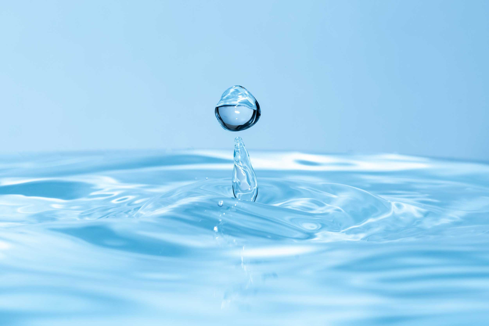 Ein Tropfen kalkfreies Wasser fällt auf die Oberfläche und erzeugt Wellen