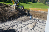 Baustellenbild mit verlegten Kunststoffrohren und Bagger