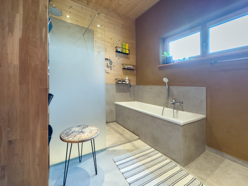 Bad mit Badewanne und Dusche und Boden und Teil der Wände aus Tadelakt (wasserbeständiger Kalkputz)