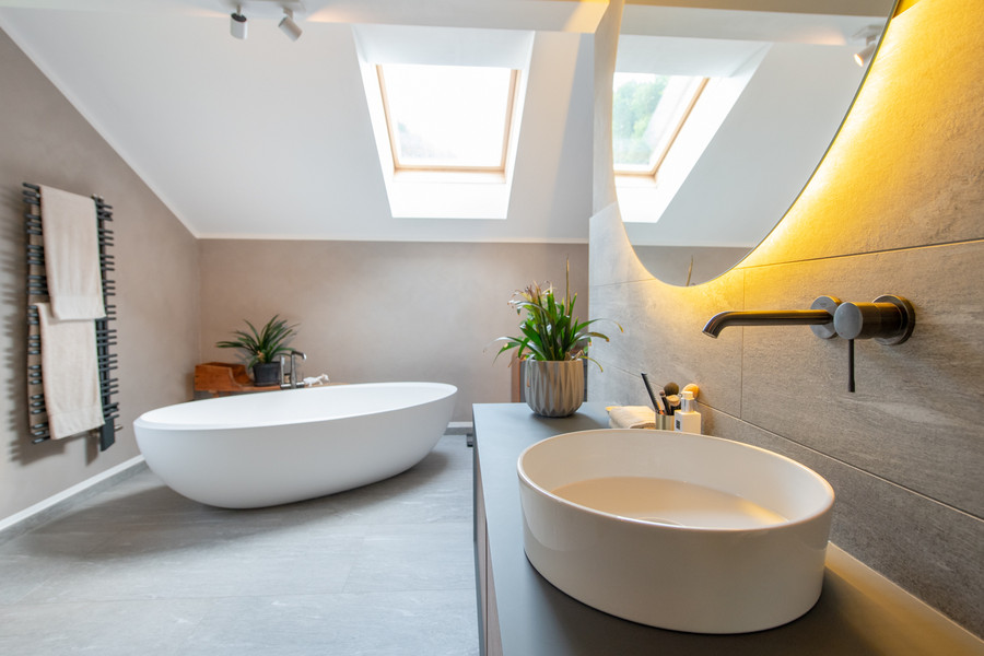 Blick ins Badezimmer mit Waschtisch mit rundem Aufsatzwaschbecken und freistehender Badewanne