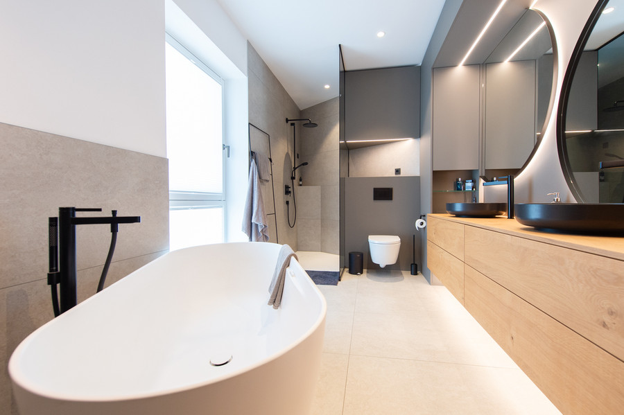 Komplettbad mit freistehender Badewanne und trendigen schwarzen Armaturen und Waschbecken
