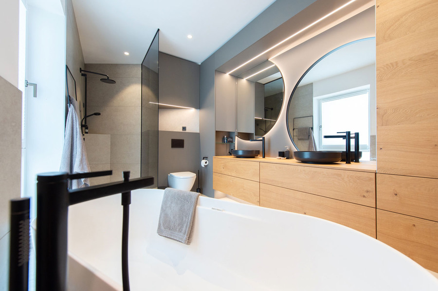 Blick über freistehende Badewanne ins Bad mit Dusche, wandhängedem WC und großem Waschtischverbau