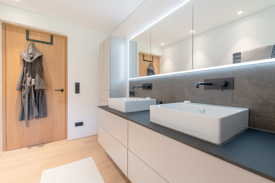 Saniertes Badezimmer mit Möbelwaschtisch und zwei Aufsatzwaschbecken und Holzboden