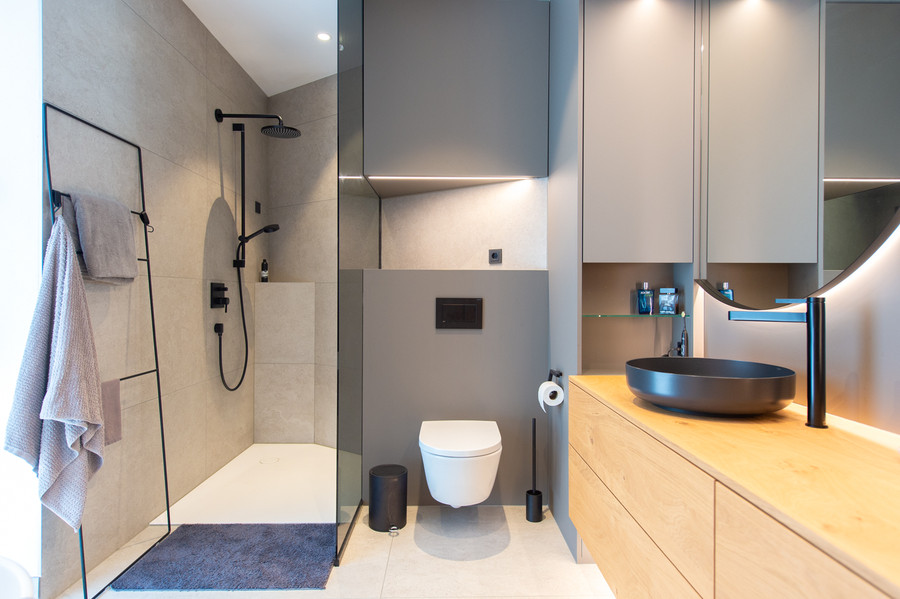 bodenebene Dusche mit Glasabtrennung und Handbrause, wandhängedem WC und Waschtisch mit trendiger Armatur und Waschbecken in schwarz