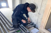 junger Arbeiter verlegt und verbindet Rohre 