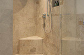 Dusche mit Natursteinfliesen und Bank