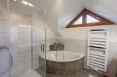 Das neugestaltete Bad mit Eckbadewanne, Dusche und Heizkörper