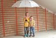 Zwei Kinder stehen mit Regenschirm vor installierten Heizungssystem