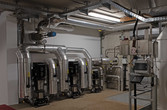 Pumpen und Pufferspeicher im Technikraum des Heizwerks