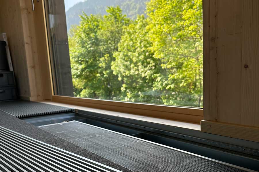 Detail: Unter dem Lüftungsgitter befindet sich ein Unterflurheizkörper.
